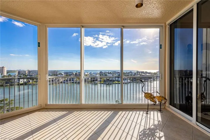 Unfurnished sunroom featuring expansive windows, a water view, and tile patterned floors