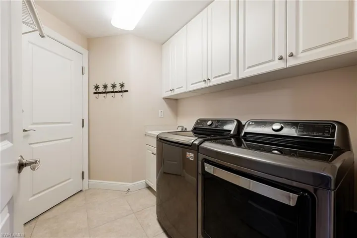 Laundry room featuring washing machine and clothes dryer, light tile patterned flooring, and cabinet space