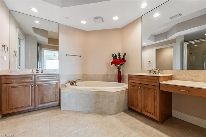 Full bath with two vanities, recessed lighting, a bath, a stall shower, and light tile patterned floors