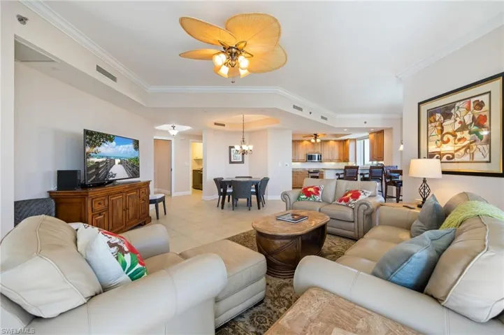 Living area featuring a ceiling fan, ornamental molding, light tile patterned floors, and a chandelier