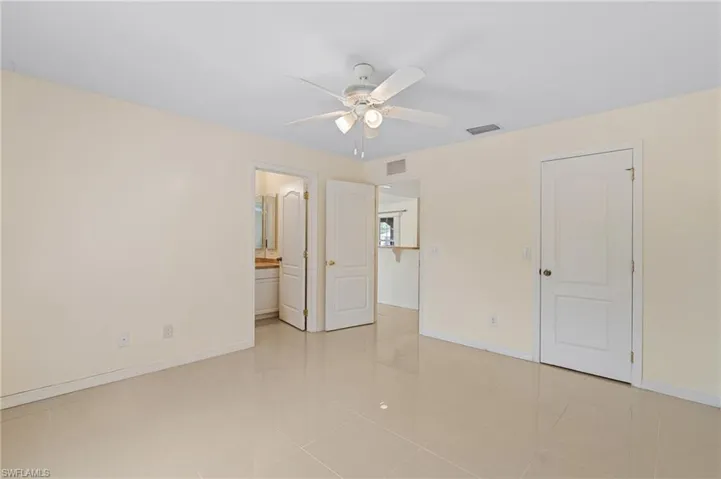 Unfurnished bedroom featuring a ceiling fan, ensuite bath, and light tile patterned floors