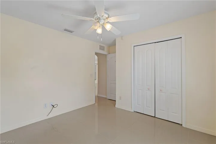Unfurnished bedroom with ceiling fan, a closet, and light tile patterned floors