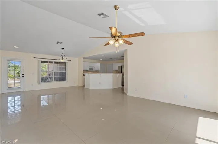 Unfurnished living room with vaulted ceiling, recessed lighting, a skylight, a ceiling fan, and light tile patterned flooring