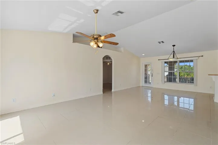 Spare room with a ceiling fan, lofted ceiling, arched walkways, and light tile patterned flooring