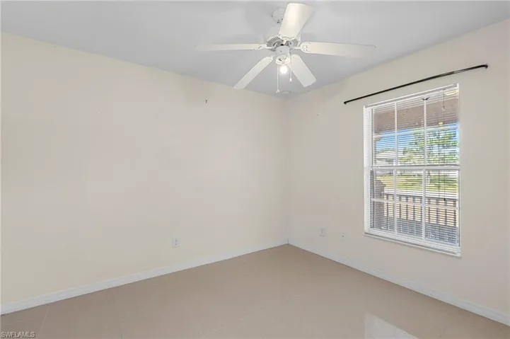 Empty room with a ceiling fan and light tile patterned flooring