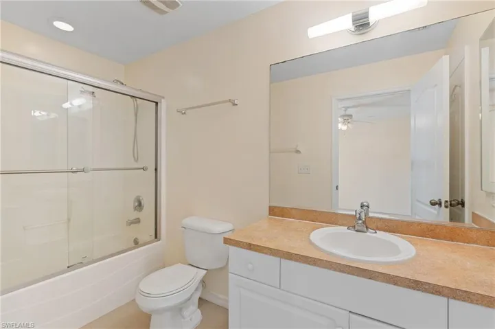 Bathroom with enclosed tub / shower combo, vanity, ceiling fan, and light tile patterned floors
