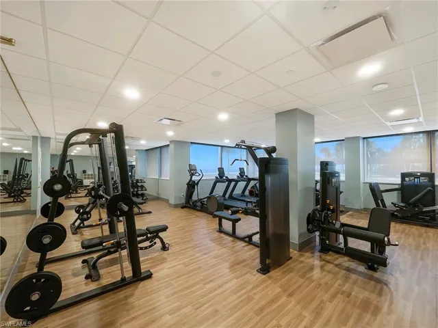 Workout area with a drop ceiling, light wood-style floors, and recessed lighting