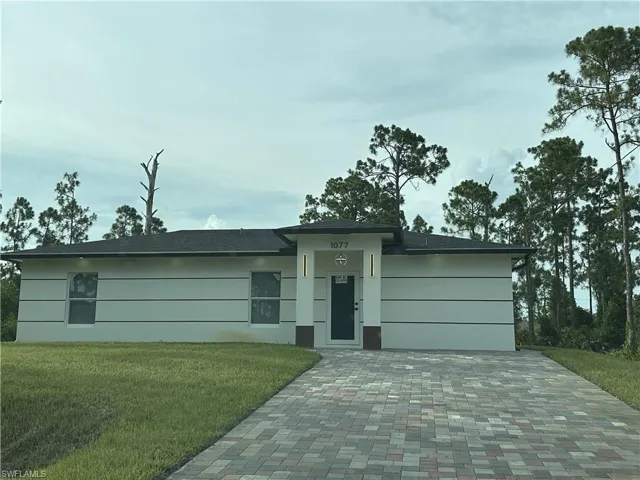 Contemporary exterior with horizontal accent banding, dark-frame windows, and a paver driveway