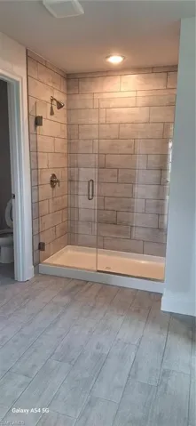Bathroom with toilet, visible vents, baseboards, and a shower stall
