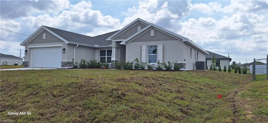 View of front of property with concrete driveway, stucco siding, central air condition unit, a front lawn, and a garage