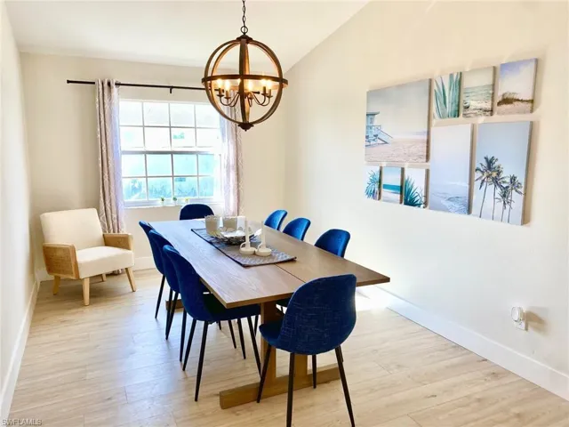 Dining area featuring light wood finished floors, a chandelier, and lofted ceiling