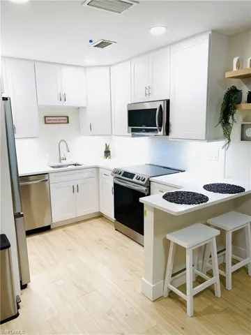 1st floor Kitchen with stainless steel appliances, a breakfast bar area, white cabinets, and decorative backsplash