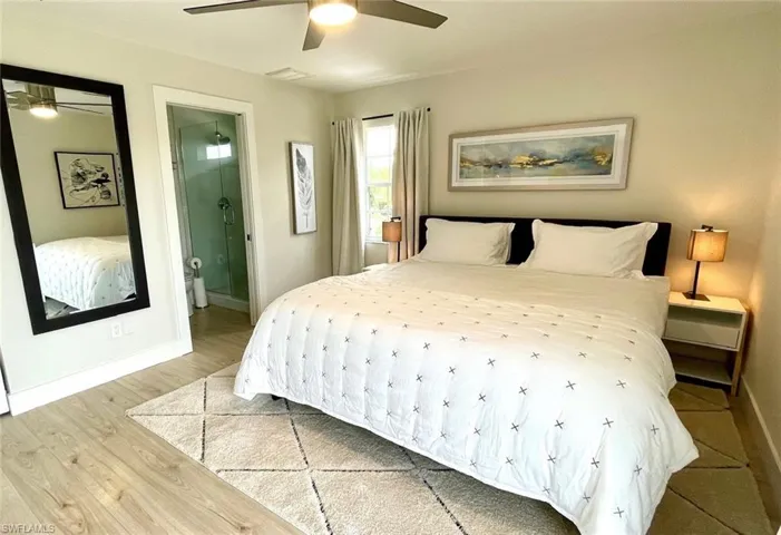 Bedroom featuring ensuite bathroom, wood finished floors, and a ceiling fan