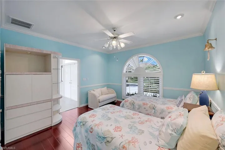Bedroom with a ceiling fan, crown molding, and dark wood finished floors