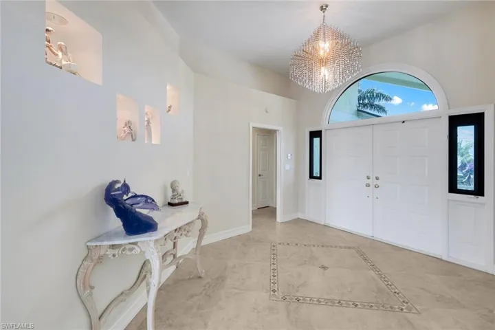 Entryway featuring hanging lights, a high ceiling, and inlaid floor details