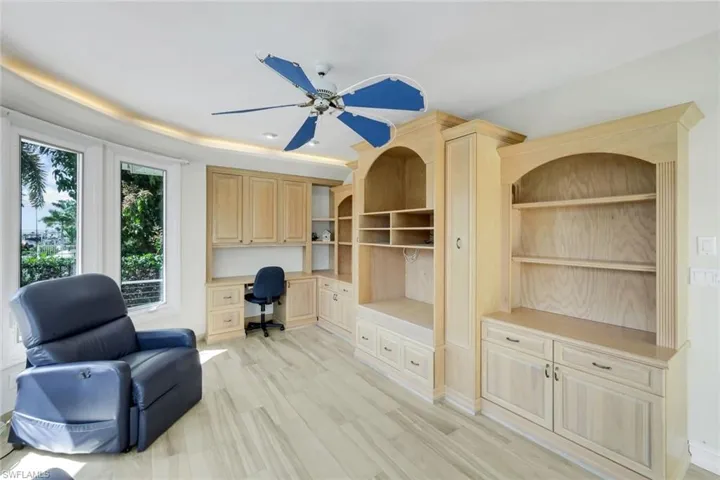 Office area featuring built in study area, ceiling fan, and light wood-style floors