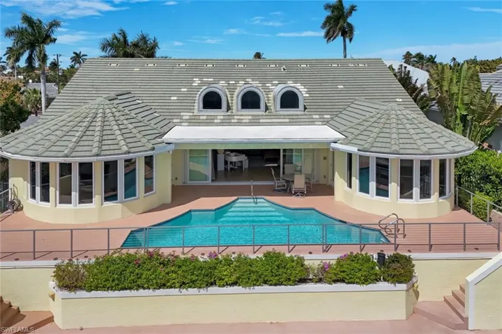 Back of house featuring a sunroom, a tiled roof, stucco siding, a patio, and an outdoor pool