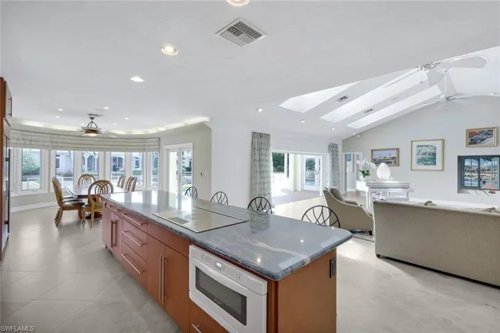 Kitchen featuring ceiling fan, open floor plan, a center island, wood finish cabinets, and a skylight