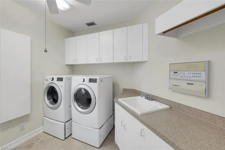 Laundry area featuring washing machine and dryer, cabinet space, and a ceiling fan
