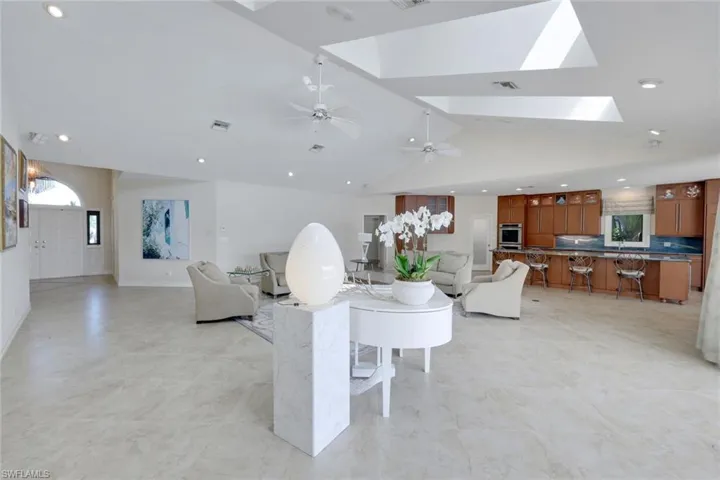 Living room with a skylight, recessed lighting, lofted ceiling, and light floors