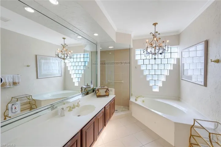 Full bath with a bath, suspended lighting, a textured wall, crown molding, and vanity