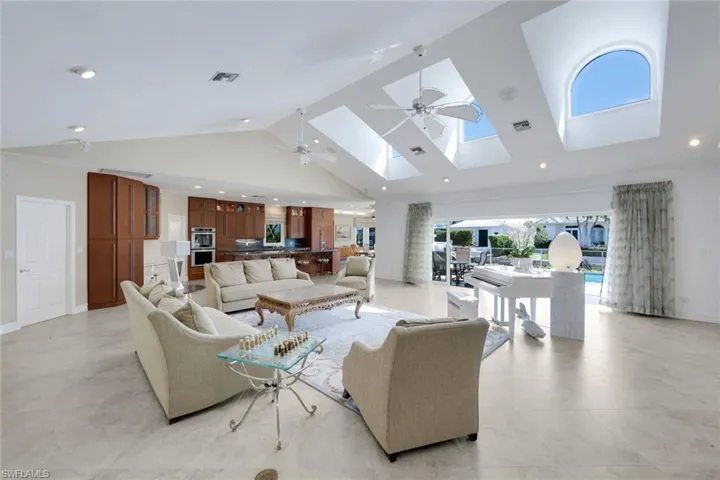 Living room with a ceiling fan, recessed lighting, a high ceiling, and a skylight