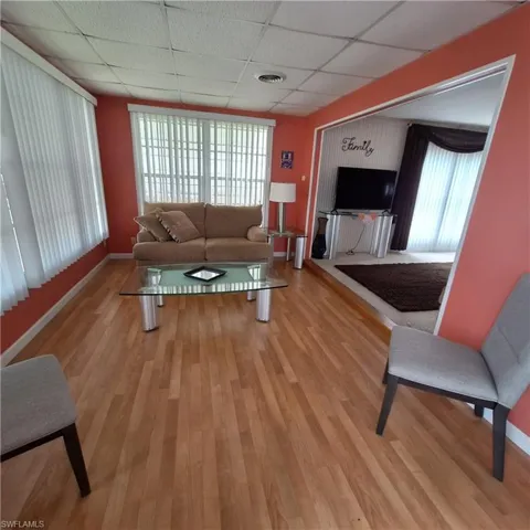 Living room with a paneled ceiling and light hardwood / wood-style floors