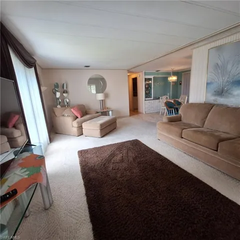 Carpeted living room with plenty of natural light and a notable chandelier