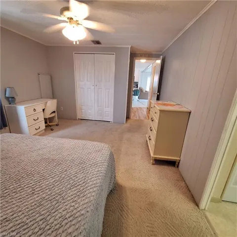 Carpeted bedroom with crown molding, a textured ceiling, a closet, and ceiling fan