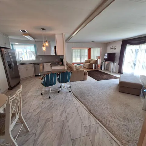 Kitchen featuring pendant lighting, sink, backsplash, stainless steel appliances, and white cabinets