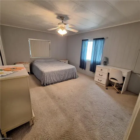 Carpeted bedroom featuring ceiling fan and ornamental molding