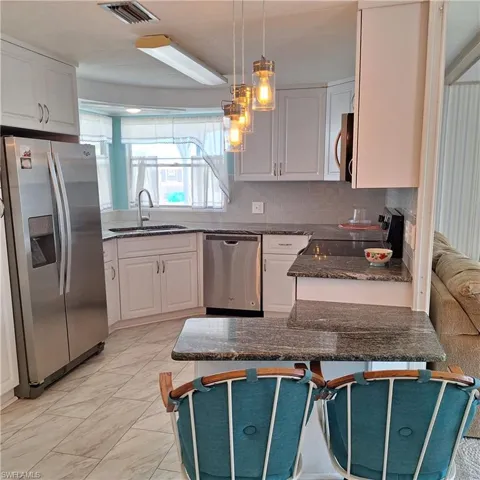 Kitchen with white cabinetry, appliances with stainless steel finishes, sink, and a breakfast bar