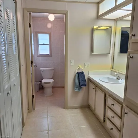 Bathroom featuring vanity, toilet, tile patterned flooring, and tile walls