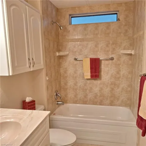 Full bathroom with vanity, tiled shower / bath combo, and toilet