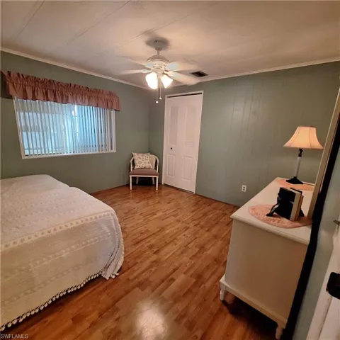 Bedroom with wood-type flooring, ornamental molding, ceiling fan, and a closet
