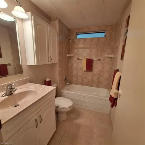 Full bathroom featuring tile patterned flooring, vanity, toilet, and tiled shower / bath