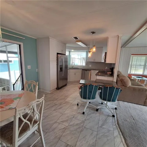 Kitchen featuring sink, white cabinetry, crown molding, decorative light fixtures, and appliances with stainless steel finishes