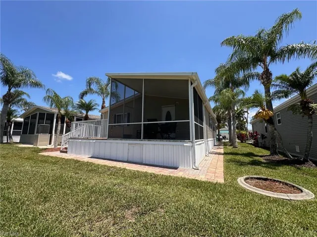Rear view of property featuring a sunroom and a lawn