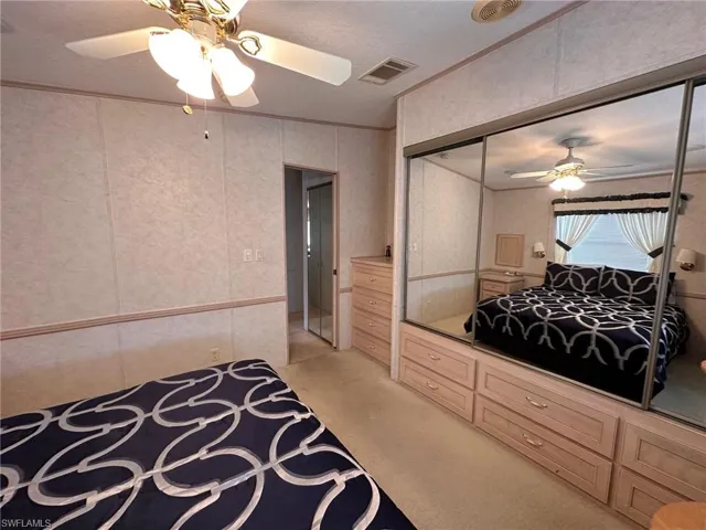 Bedroom featuring light carpet, a ceiling fan, and ornamental molding