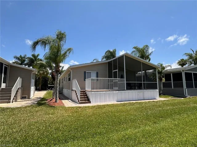 Rear view of house featuring a sunroom, stairs, and a yard