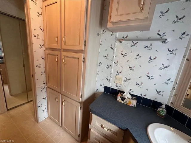 Bathroom with wallpapered walls, a sink, and tile patterned flooring