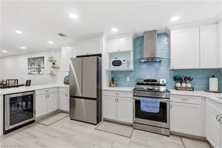 Kitchen with stainless steel appliances, white cabinets, wine cooler, open shelves, and recessed lighting