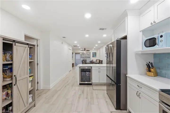 Kitchen featuring wine cooler, white cabinetry, freestanding refrigerator, a peninsula, and a barn door
