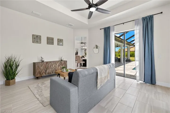 Tiled living room with ceiling fan and a tray ceiling