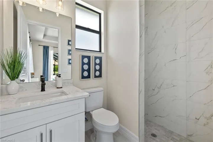 Bathroom with tiled shower, toilet, and vanity with extensive cabinet space