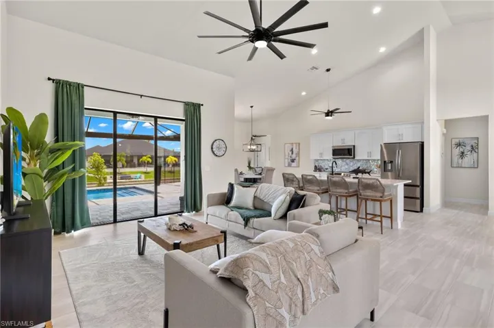 Living room featuring high vaulted ceiling, sink, and ceiling fan