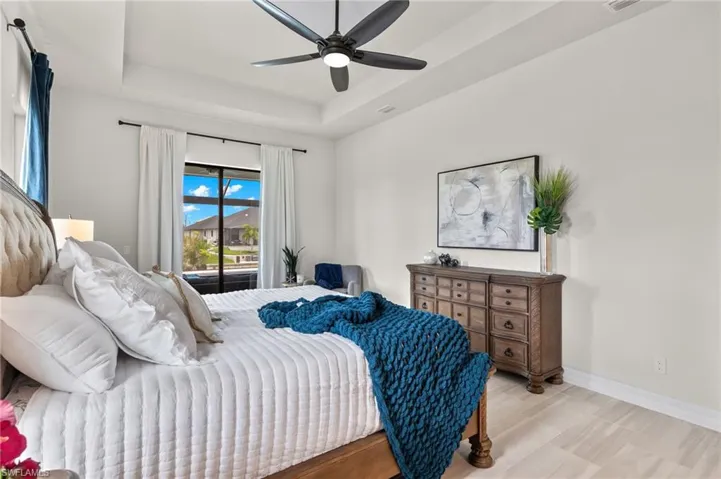 Bedroom with access to outside, a tray ceiling, and ceiling fan