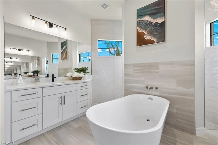 Bathroom with vanity with extensive cabinet space, a healthy amount of sunlight, and tile walls