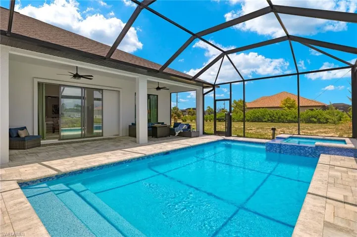 View of swimming pool featuring ceiling fan, glass enclosure, and a patio