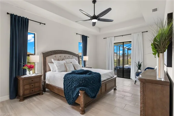 Bedroom with a raised ceiling, ceiling fan, and access to exterior